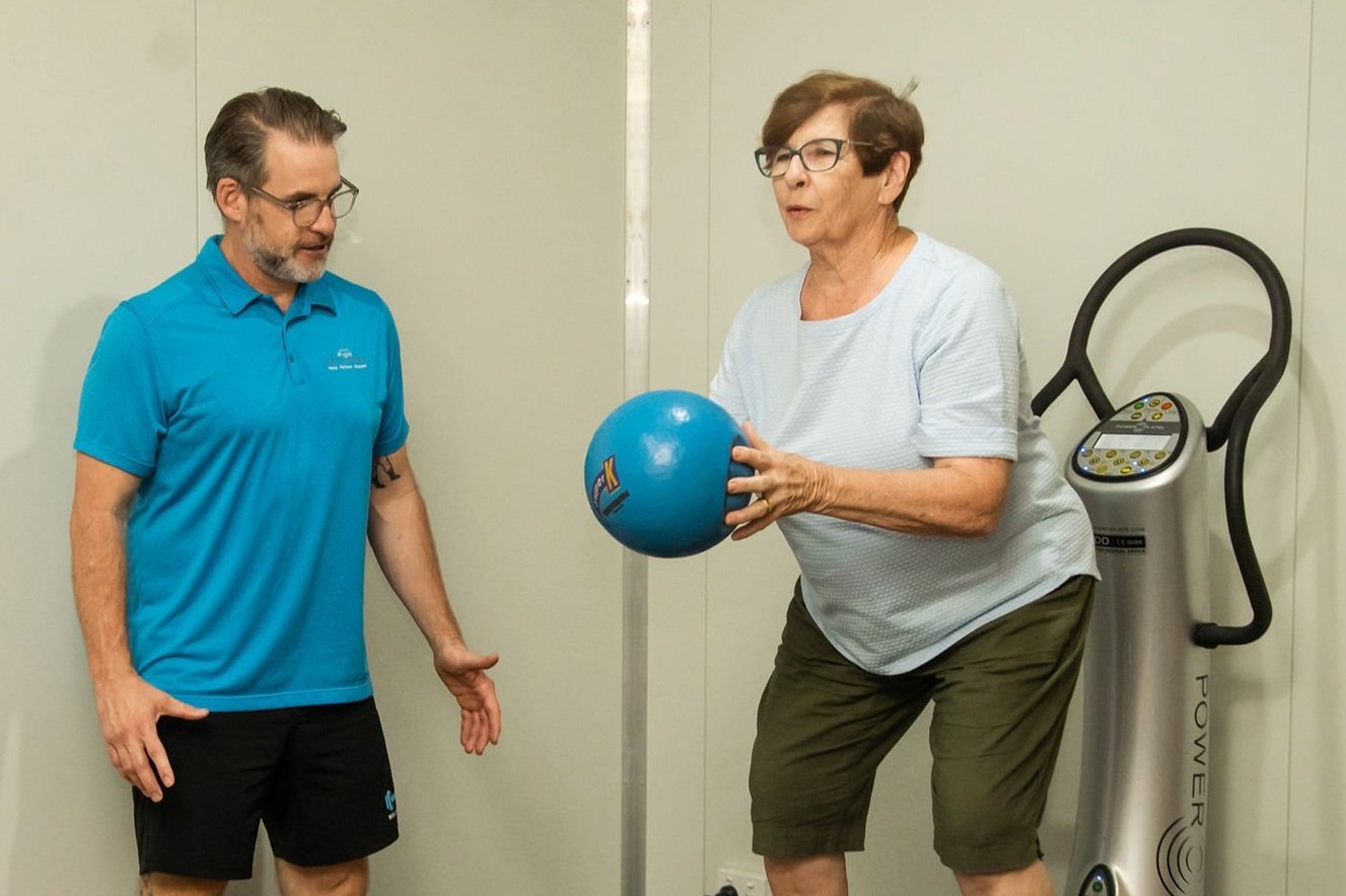Instructor Louis with one of his clients practicing an exercise with a medicine ball